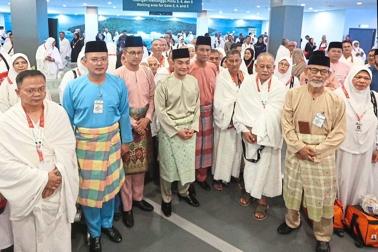 (From second left) Mohd Hairi, Mohd Fared and Onn Hafiz with haj pilgrims at Senai International Airport in Johor. — Photos: THOMAS YONG/The Star
