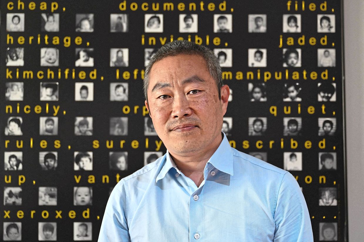 Moller posing for a photo in front of pictures of Korea-born adopted children. ­— AFP