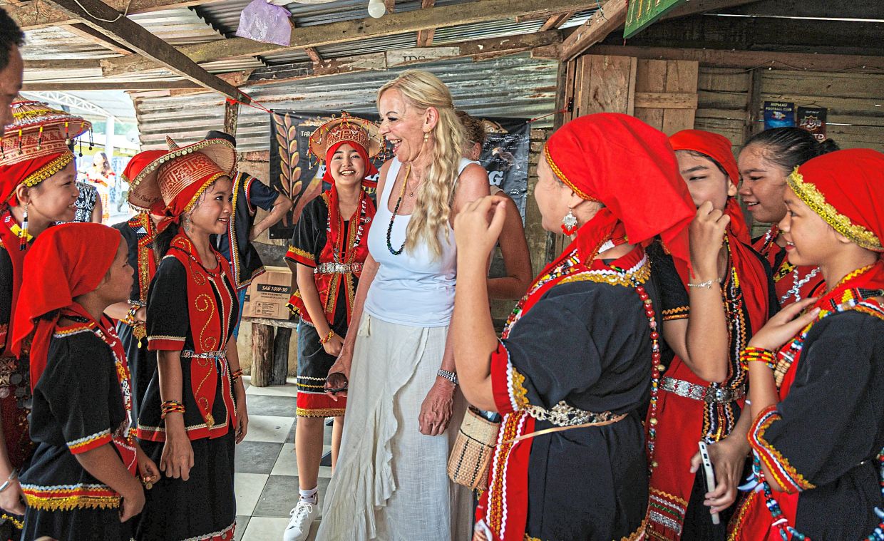 Parade participants chatting with a visitor during the Gawai celebration at Kampung Taee.