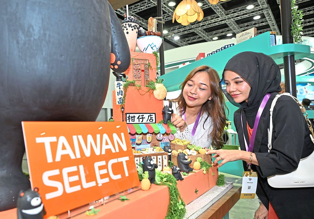 Visitors admiring a display of Taiwanese food and beverage items, such as pineapple-based snacks, mochi, noodles and black sesame based-drinks.