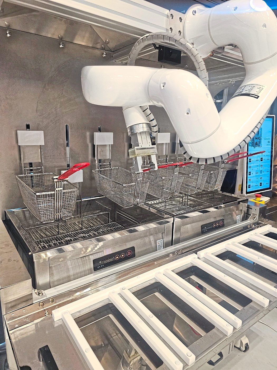 A frying robot developed by itcobot placing a container into a deep fryer during a demonstration at the 2025 Food Service Fair at Coex in southern Seoul, on April 29. — The Korea Herald/ANN