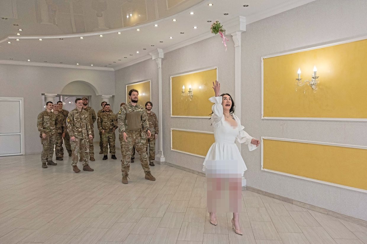 Anna throwing a bouquet of flowers for the guests during her wedding ceremony with Pavlo at a civil registry office in Sloviansk, the eastern Donetsk region. — AFP