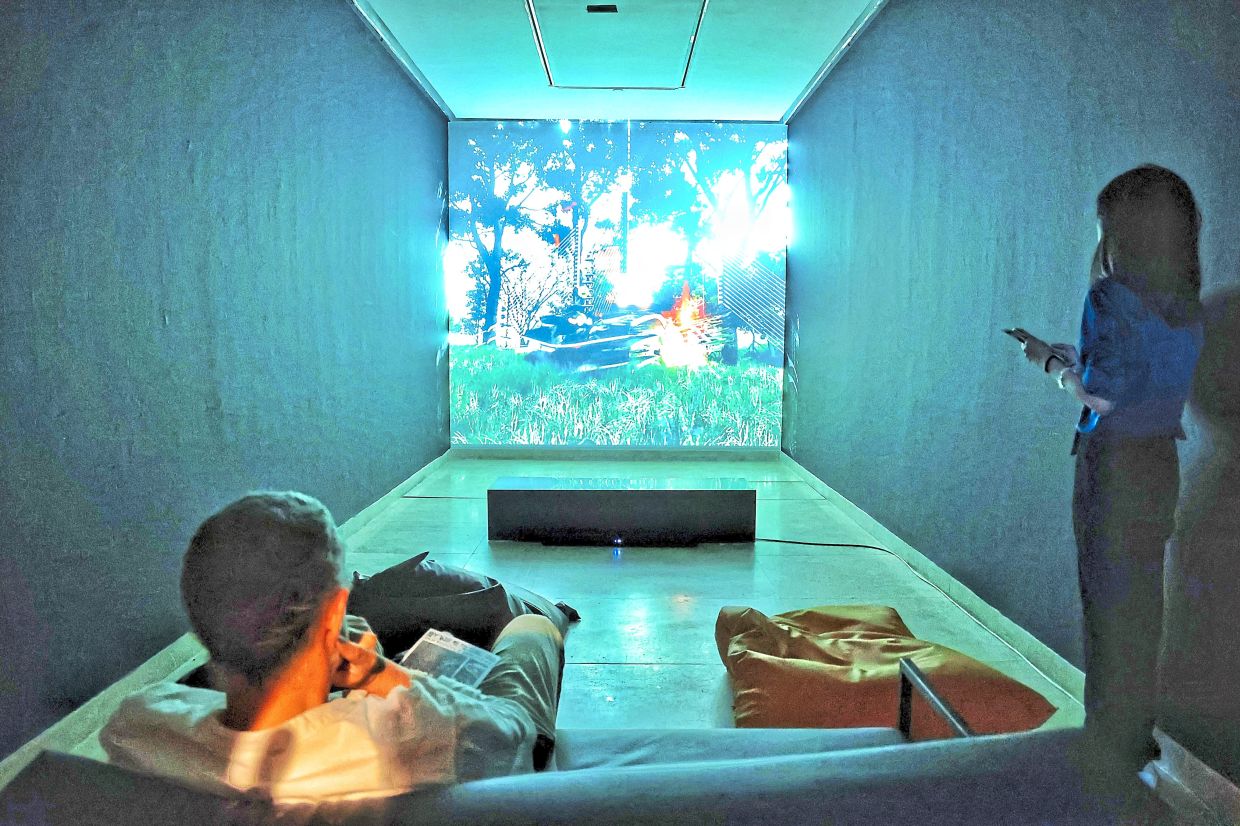 Visitors tune into Chong Yan Chua’s 'Apa-Cita?', a CGI-driven video work that probes the intersections of technology and ritual in the age of digital shamanism. Photo: The Star/Muhamad Shahril Rosli