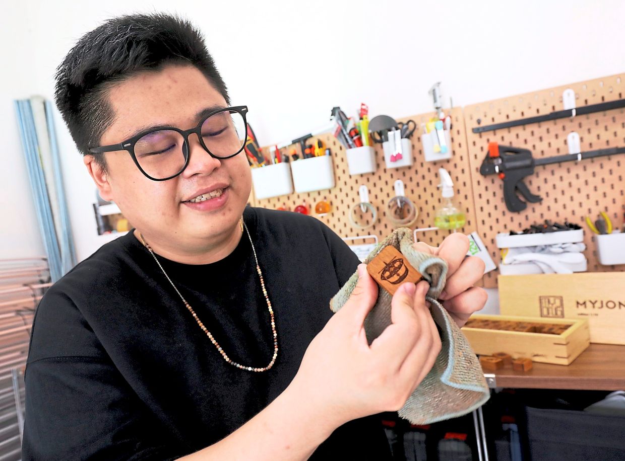 Ng holding a MyJong tile with a wau motif.