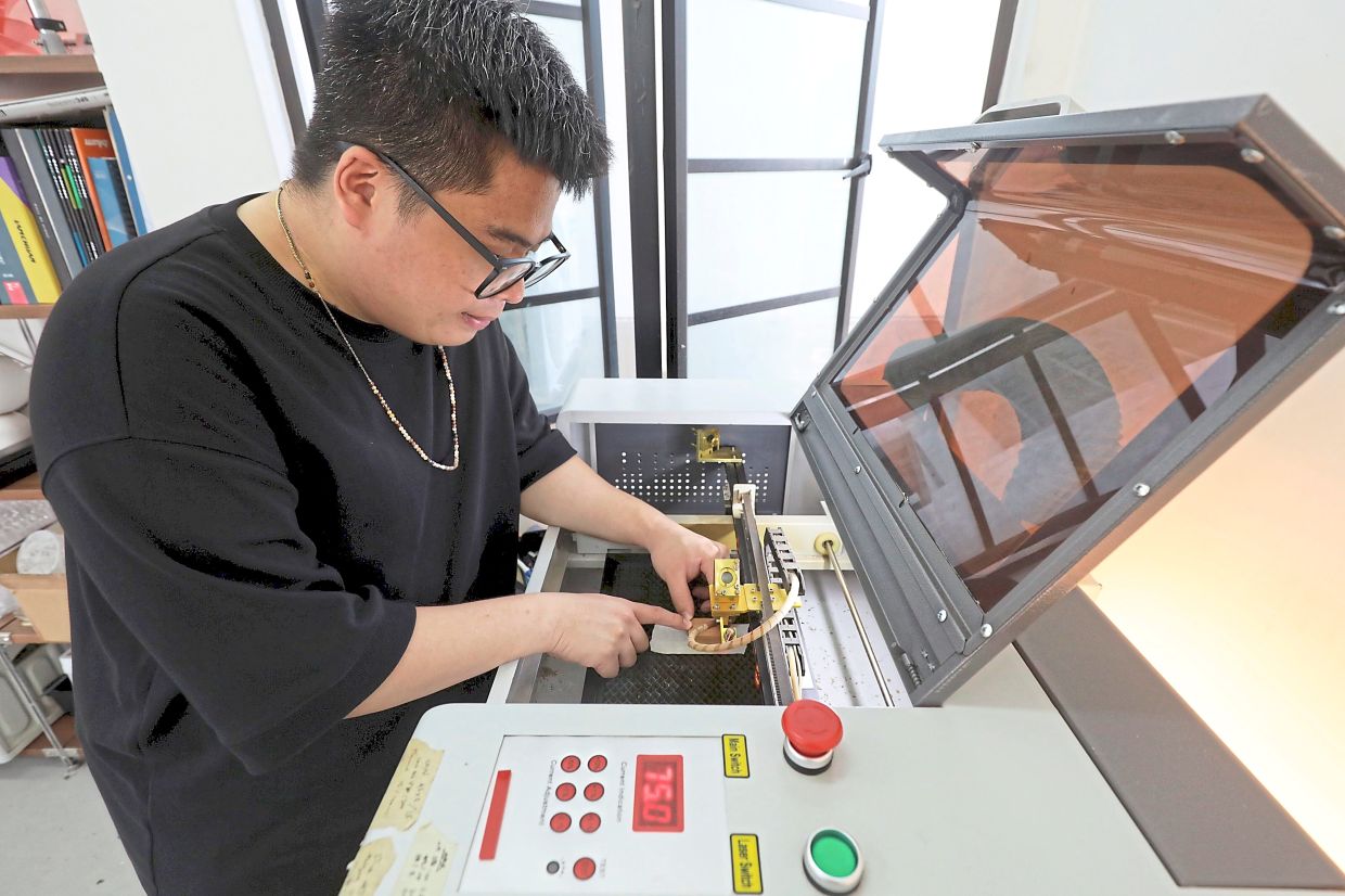Ng uses a laser engraver to etch the design onto each tile.