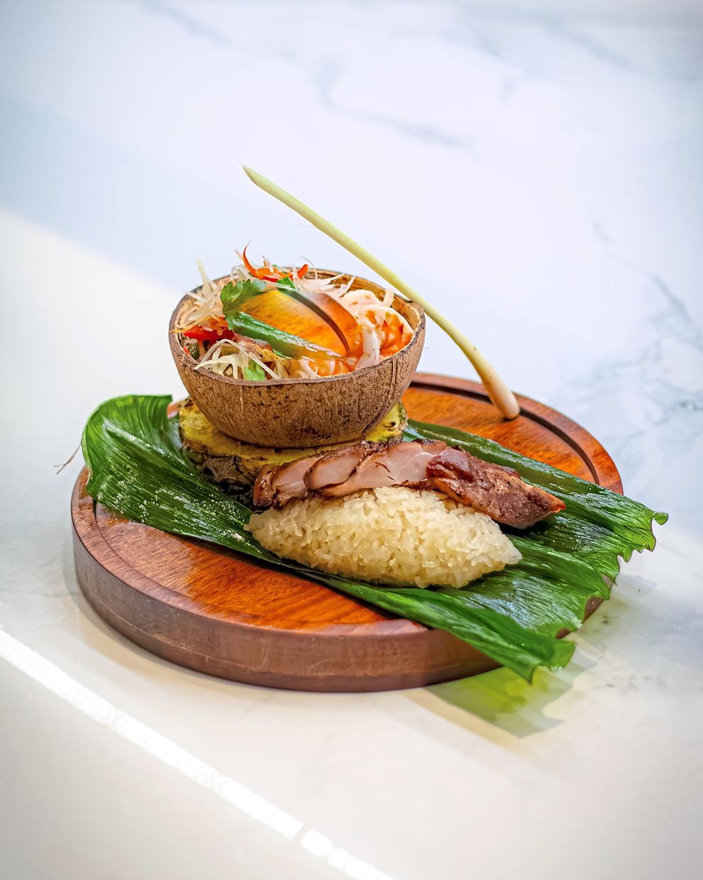 Som Tam Goong served atop sticky rice and grilled chicken.