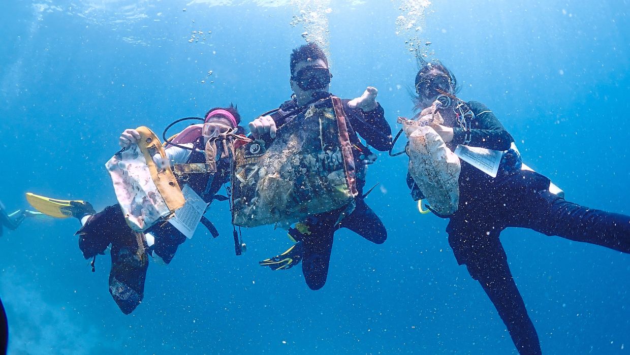 Reef Check Malaysia members showcasing the plastic waste collected during an ocean cleanup activity.