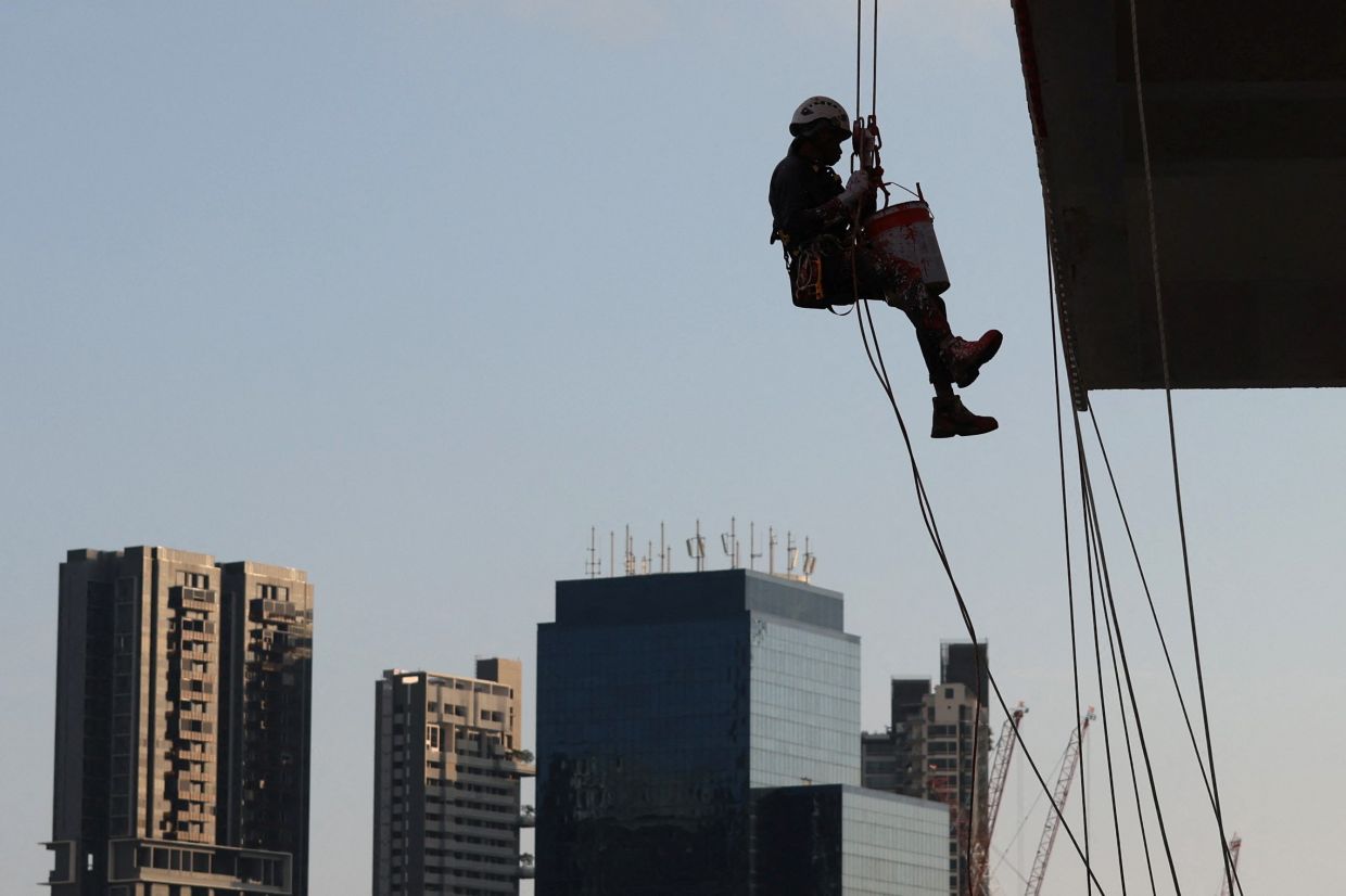 A worker paints the facade of a building in Singapore . - REUTERS/Edgar Su