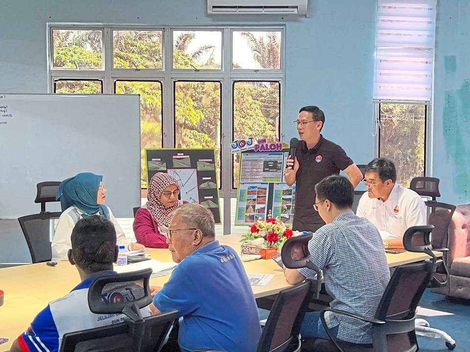 Lee speaking during a meeting with government agencies and community leaders regarding the project while Tan (right) looks on.