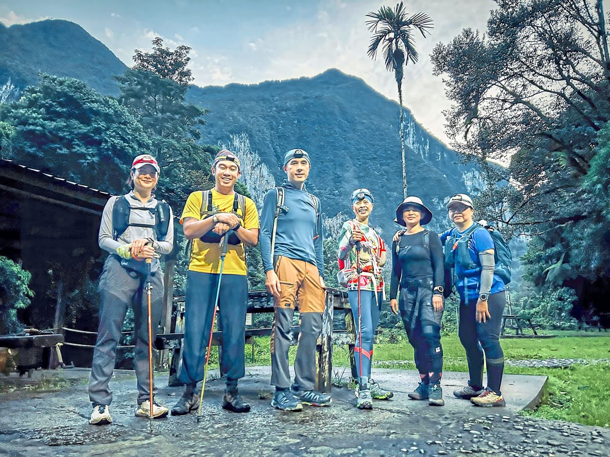The Trailblazer Hiking Club team stands ready at Camp 5, with the limestone cliffs of Gunung Benarat rising behind them.
