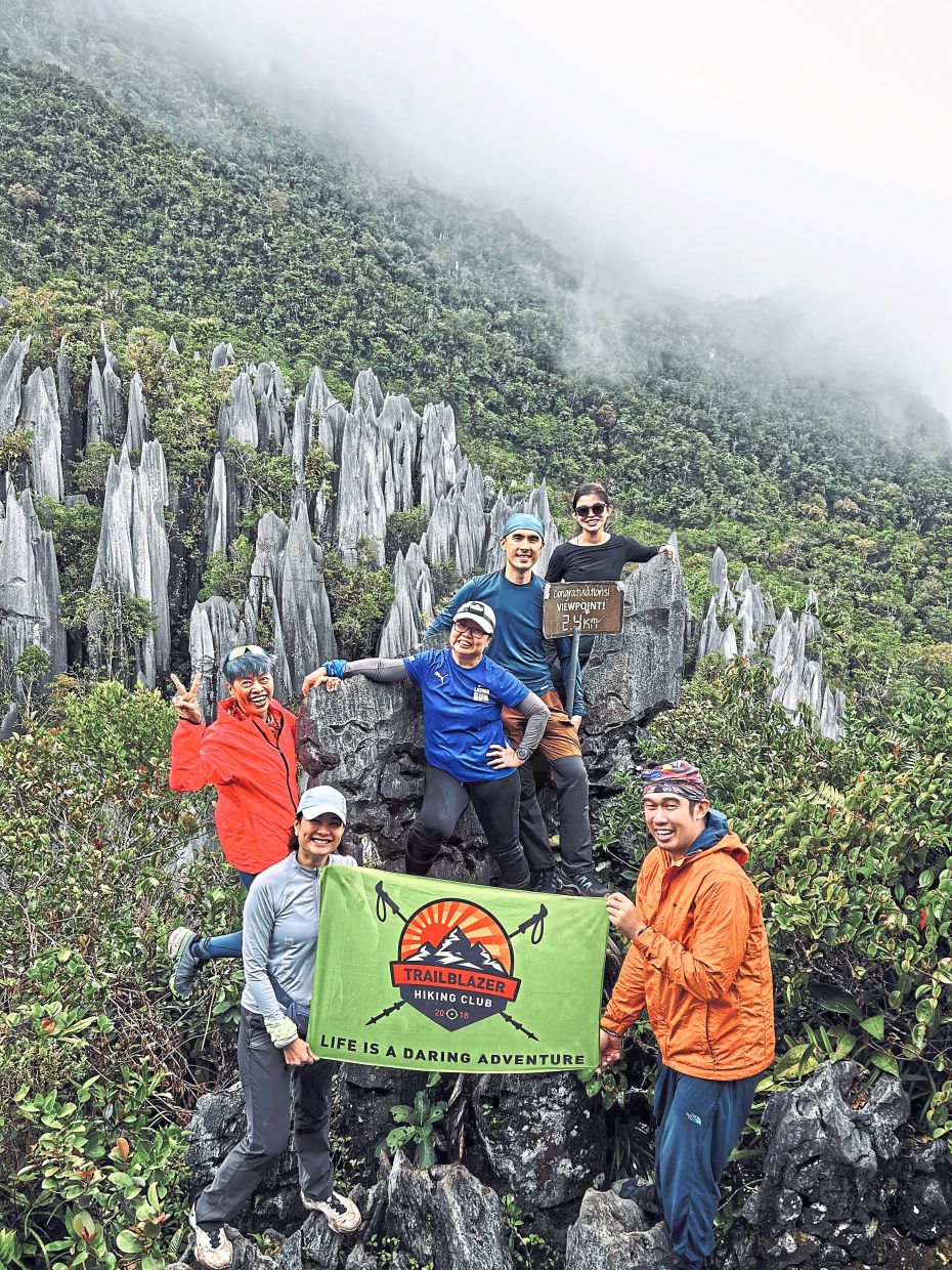 The Trailblazer Hiking Club team celebrates reaching the Pinnacles viewpoint after a vertical challenge through Sarawak’s deep jungle.