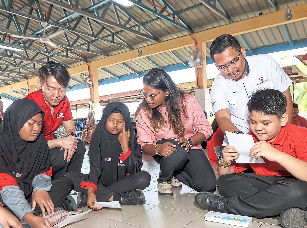 SMG Brand Studio general manager Chia Mei Yeng (left) and TNB Kelantan retail head Khabir Sufi Berhanuddin (right) helping students with the programme activities.