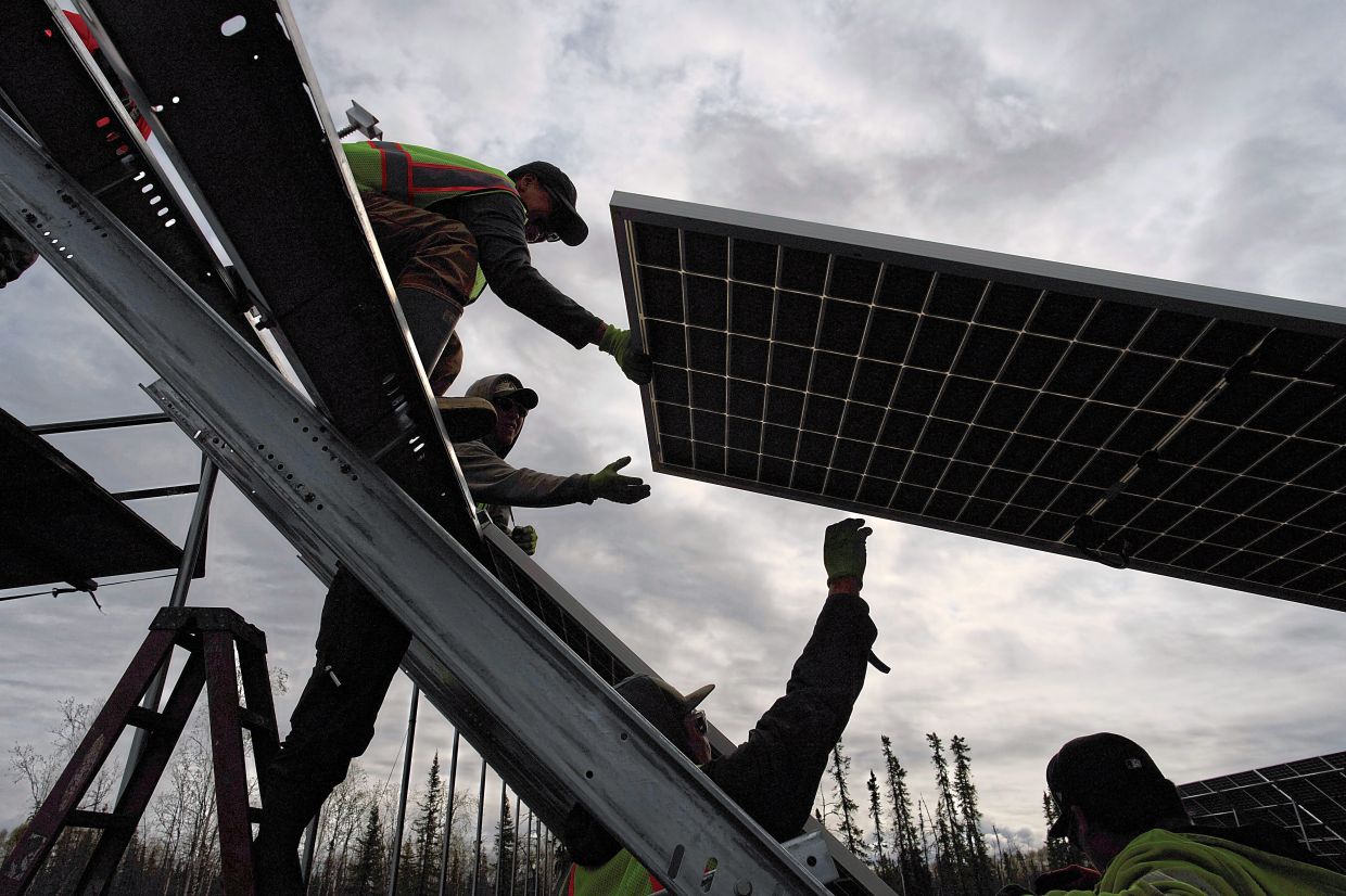 Workers install panels at a solar project.