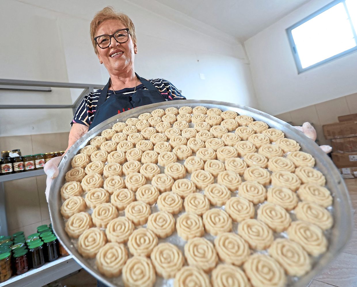 Qerimi shows traditional Albanian sweets with rose water on a tray.