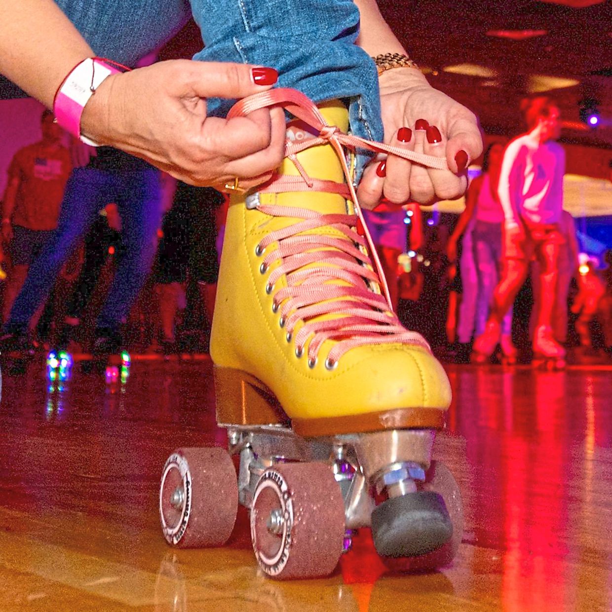 A roller-skater tightens her skates next to the rink.