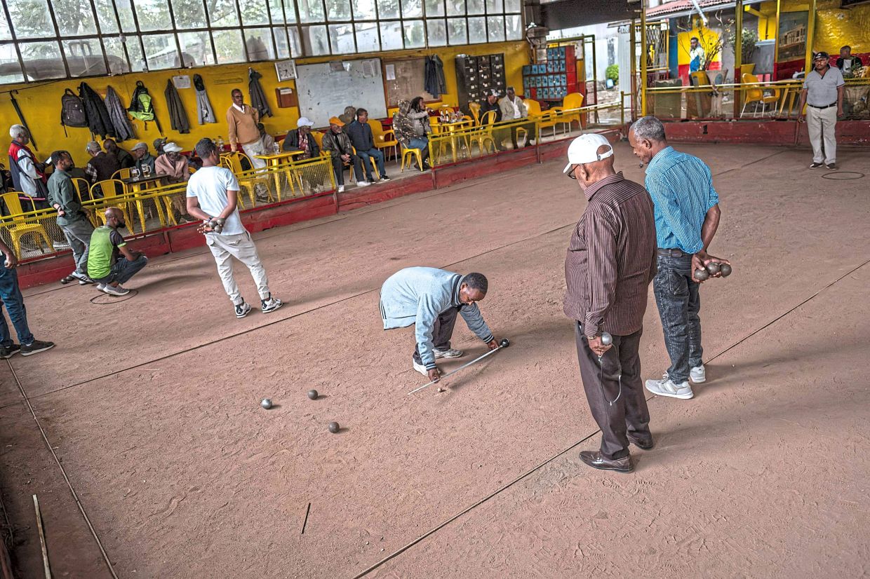 A club member measures the distance between a boule and the jack with a tape measure during a petanque match at the Club des Cheminots.