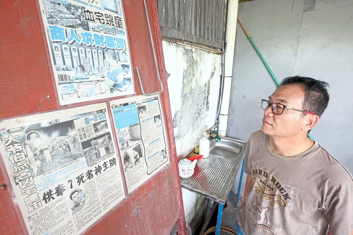 (Left) Temple volunteer Chen looking at newspaper articles on the murders that took place at the house in 2001. — THOMAS YONG/The Star