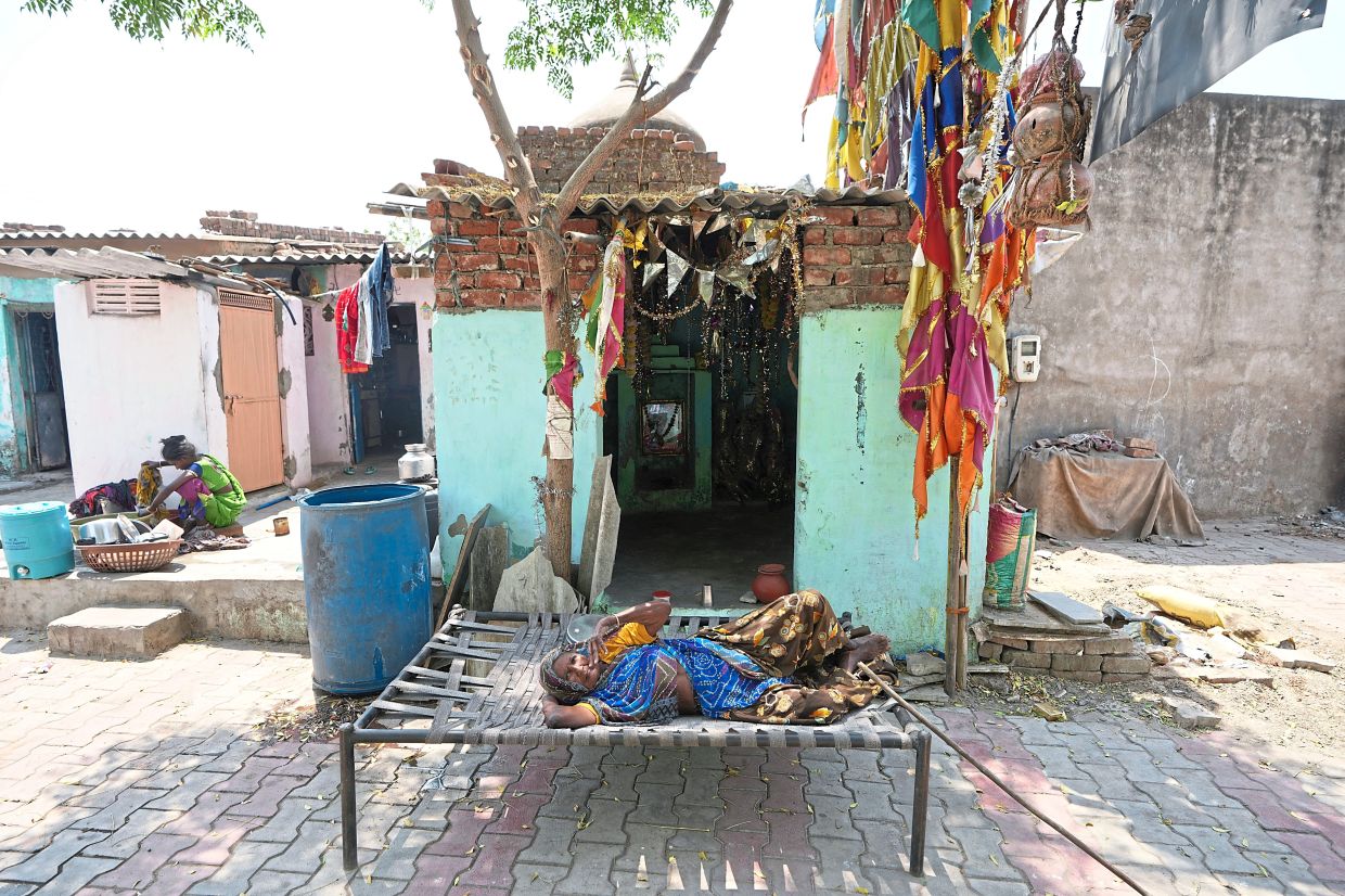 Chilling out: An elderly woman resting in the shade of a tree in Ahmedabad. — AP