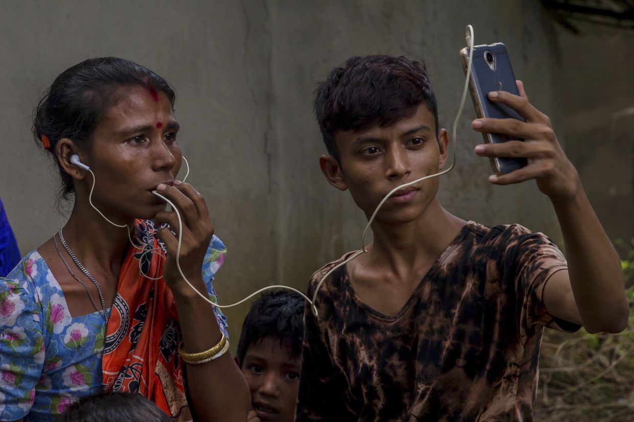 Sarasvati Devi talks to her mother in Myanmar via video call as Ranjan, her brother, holds the phone, outside a camp for Hindu refugees near Kutupalong, Bangladesh, Sept. 26, 2017.