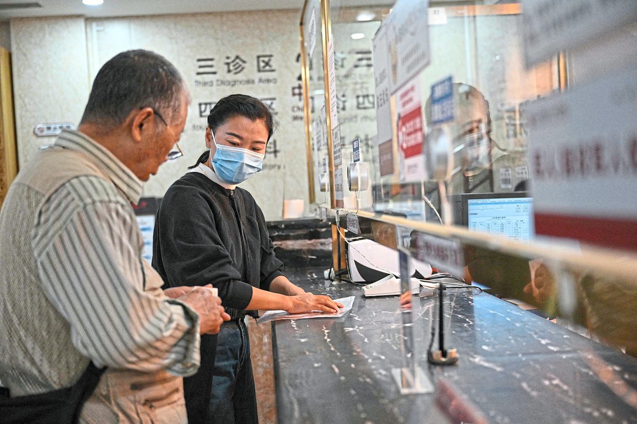 Trusted assistant: Meng (right) assisting Tian at the payment counter during their visit to a traditional Chinese medicine hospital in Beijing. (Below) Meng listening to Gao. — AFP
