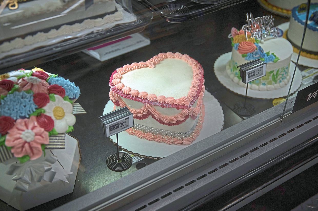 Cakes being displayed inside a Walmart in North Bergen; and (below) an employee decorating a cake. — AP