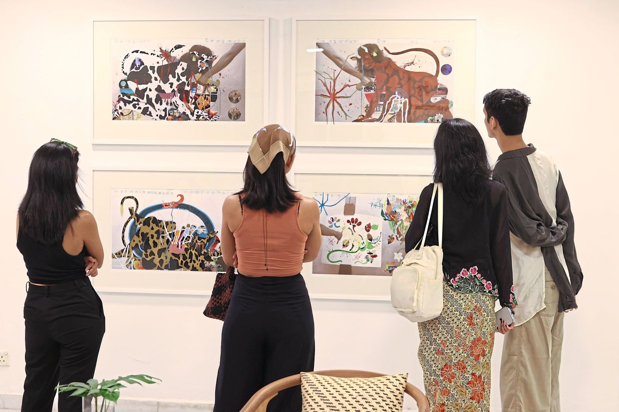 Visitors view four works from Binti's 'Cow Dan Aku' series at the 'Sesuatu Yang Something' opening. Photo: The Star/Glenn Guan
