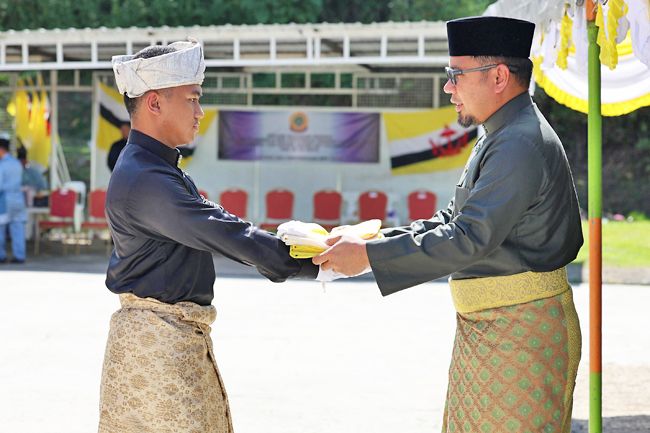 Acting Brunei-Muara District Officer Pengiran Muhammad Ameer Mubaarak Pengiran Hashim hands over a national flag. - Photo: Borneo Bulletin