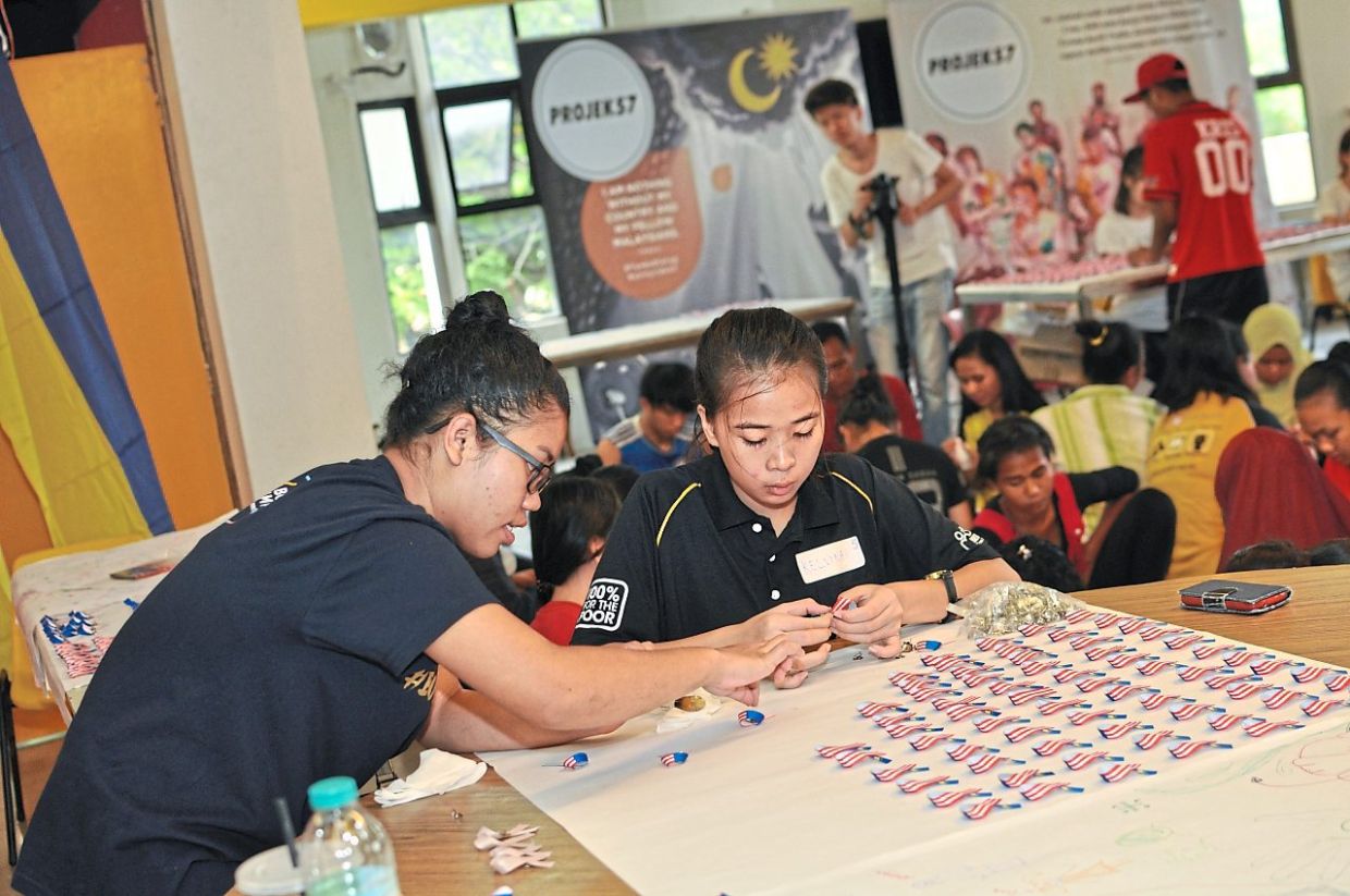 Working together: Youth making unity ribbons at a Projek57 workshop. — The Star