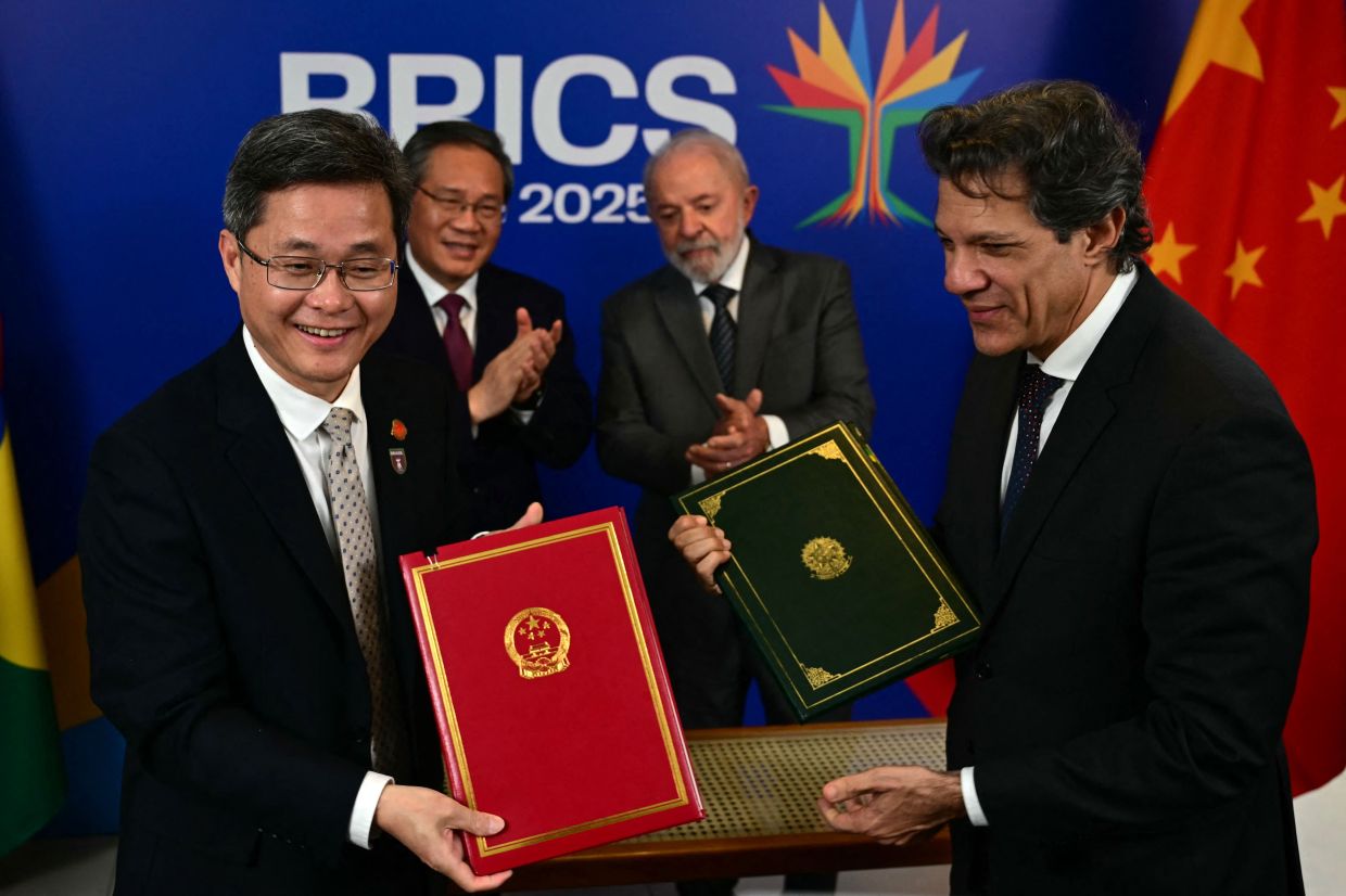China's Finance Minister Lan Fo'an (left) and Brazil's Economy Minister Fernando Haddad pose for a picture next to China's Premier Li Qiang and Brazil's President Luiz Inacio Lula da Silva after signing a bilateral agreement, in the sidelines of the BRICS summit in Rio de Janeiro, Brazil. BRICS leaders meeting in Rio de Janeiro from Sunday (July 7) are expected to decry Donald Trump's hardline trade policies, but are struggling to bridge divides over crises roiling the Middle East. -- Photo by Pablo PORCIUNCULA / AFP