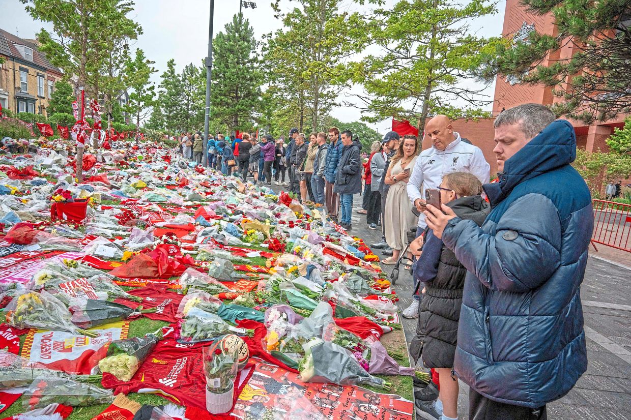 Well-wishers view flowers, scarves and shirts at a memorial set up close to Anfield football ground for their Portuguese forward Diogo Jota in Liverpool on July 4. — AFP