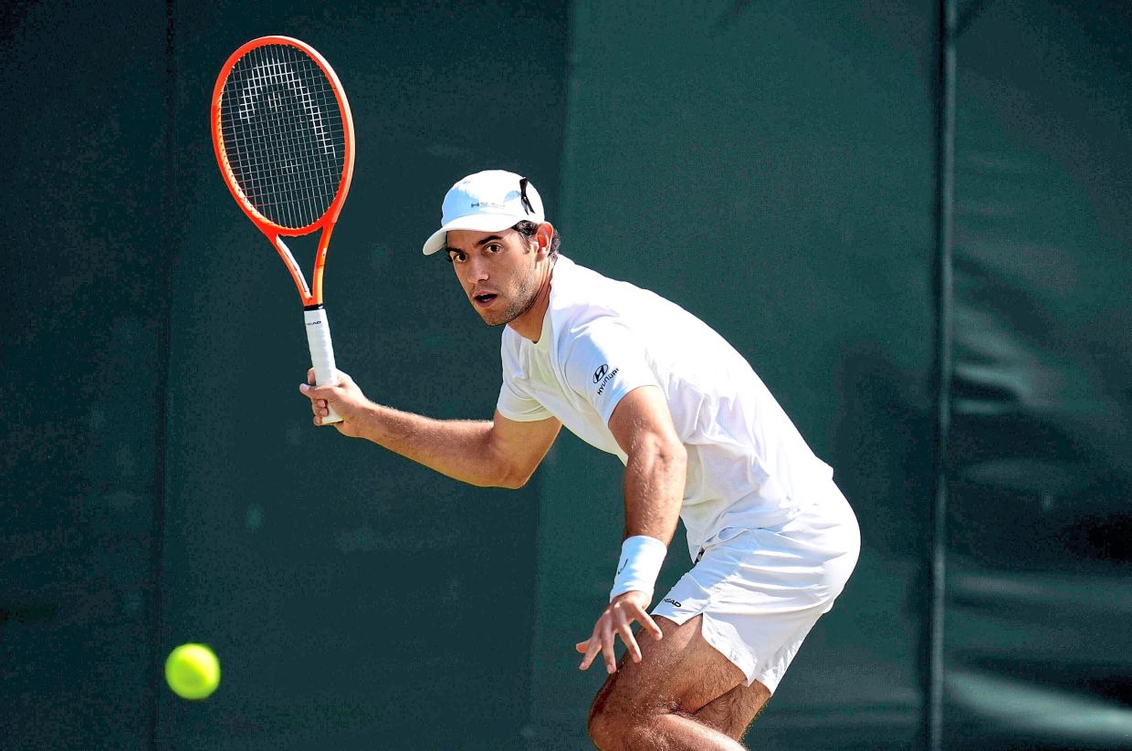 Nuno Borges of Portugal, wearing a black ribbon in his hat in memory of compatriot Diogo Jota returns to Karen Khachanov of Russia during their men's singles match on day five of the Wimbledon Tennis Championships in London, Friday July 4, 2025. (Mike Egerton/PA via AP)