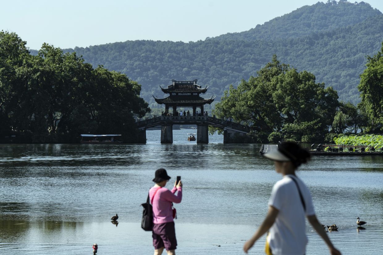 Visitors by West Lake in Hangzhou, China. Many in the crowd in Tao’s backyard said the atmosphere in Hangzhou, set on the banks of a lake that was muse to generations of Chinese poets and painters, fueled their creativity.