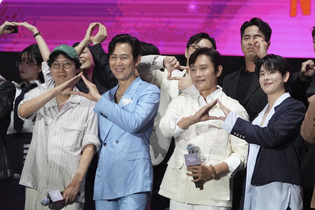 Actor Lee Jung-jae, second from left, director Hwang Dong-hyuk, left, actor Lee Byung-hun, second from right, and actor Yim Si-wan, right, gesture during the Squid Game Season 3 finale fan event in Seoul, South Korea, Saturday, June 28, 2025. (AP Photo/Lee Jin-man)