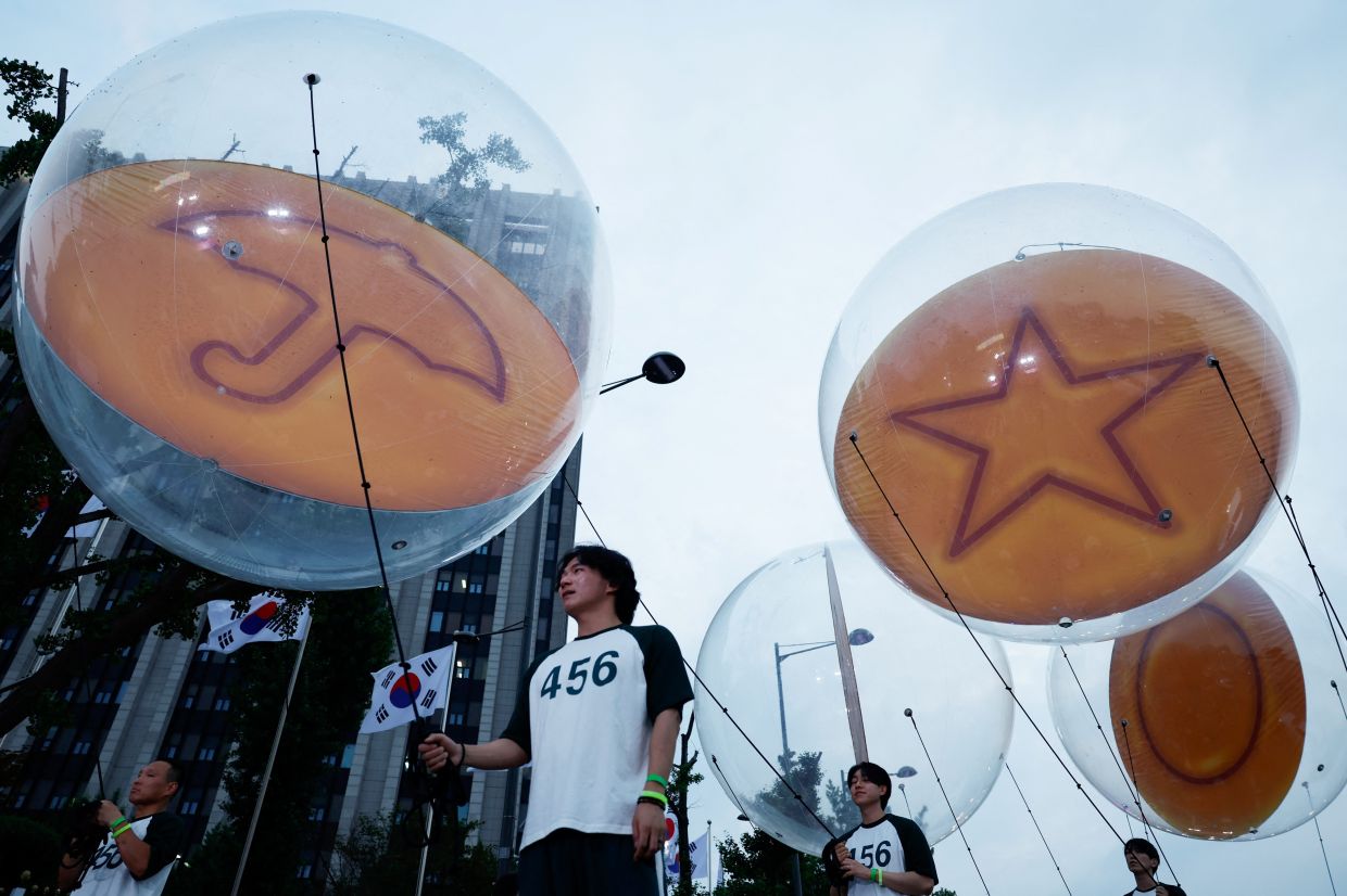 Performers dressed as the 'Squid Game' participants hold dalgona-themed balloons, before a parade through central Seoul, followed by a fan event with cast to celebrate the release of the third season of Netflix's hit series, in Seoul, South Korea, June 28, 2025. Photo: Reuters