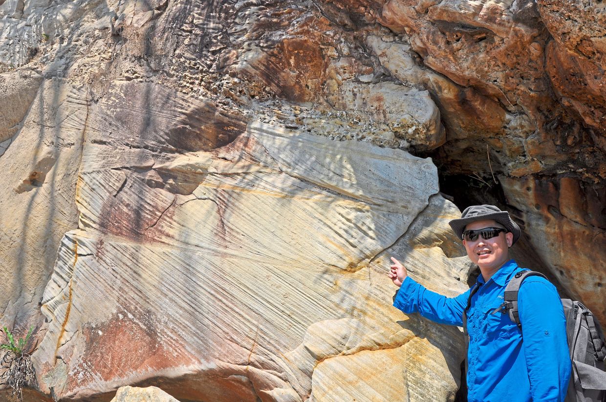 Simon next to a rock formation that shows cross-bedding indicative of a past river environment,Gerbang laut formation and Kinabenuwa wetlands.