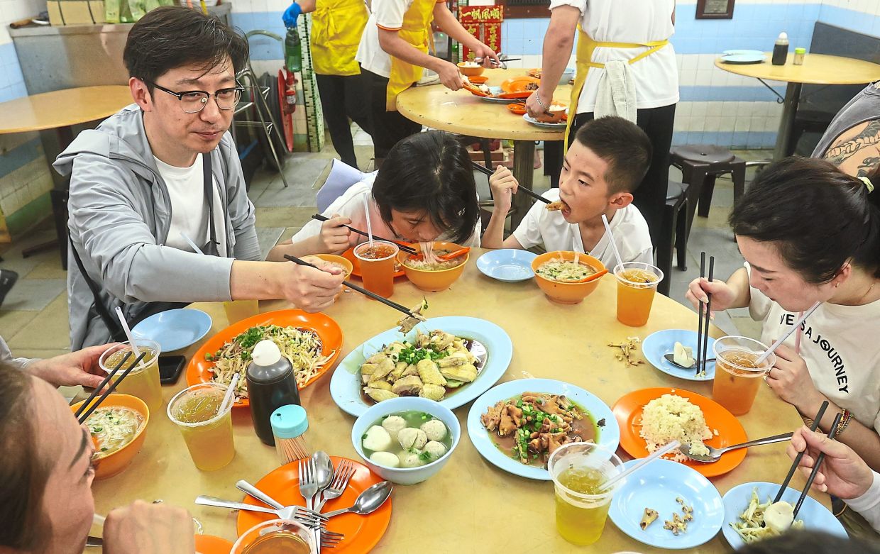 Lee Jun,40 ( left) from Shanghai,China and his family,enjoying the famous Bean Sprout Chicken Rice with his family on Jalan Yau Tet Shin Ipoh-(7th July 2025)--RONNIE CHIN'/The Star