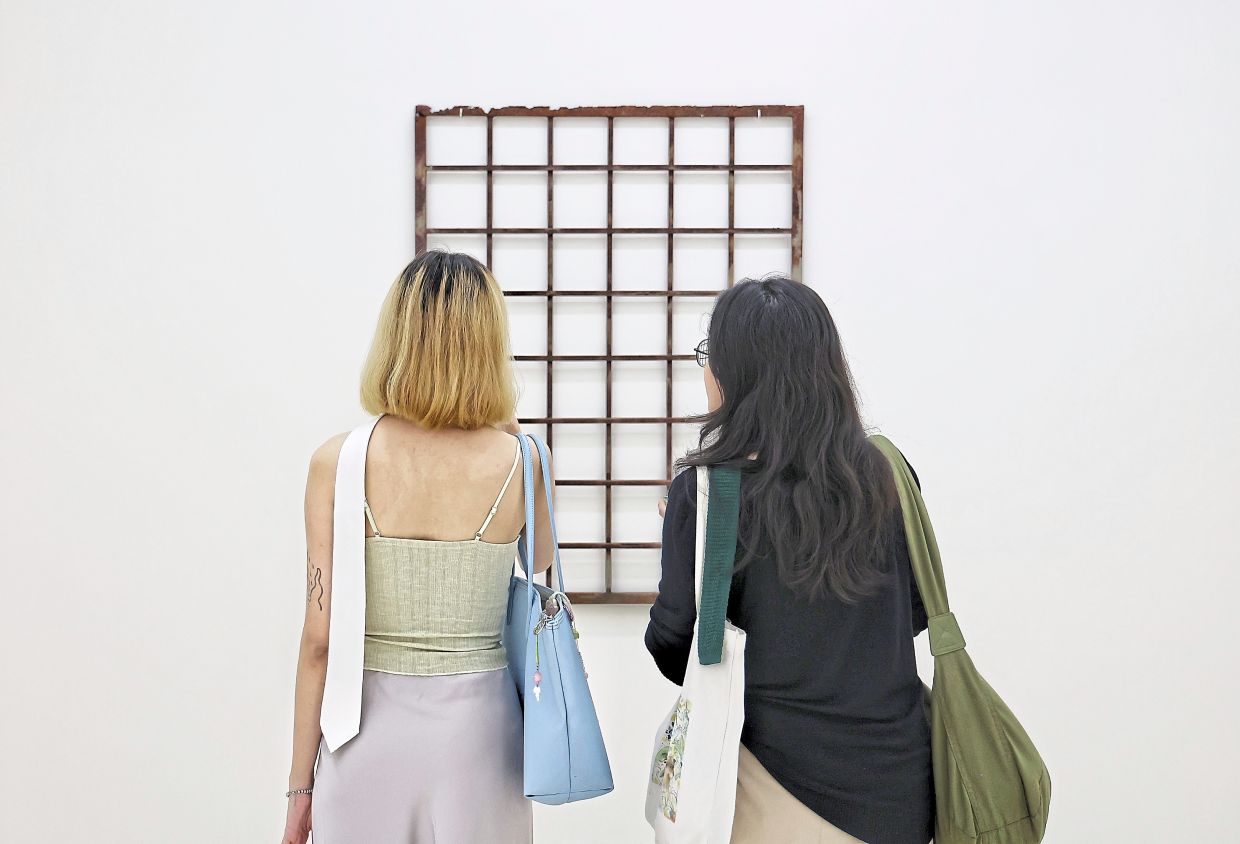 Visitors view the old window grille from Ain’s family home, replaced with a new fire-access design.