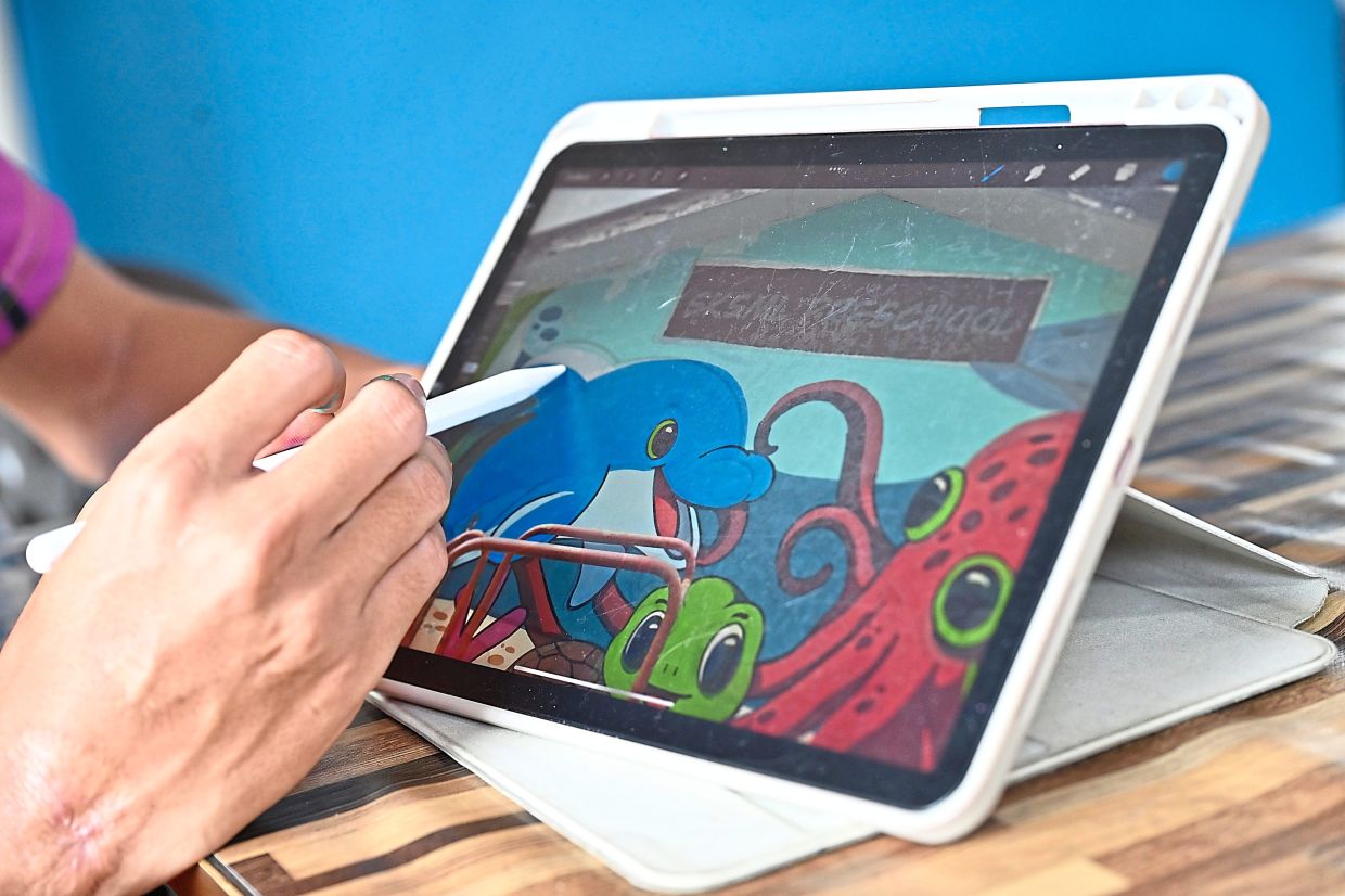 Mohamad Firdaus uses an app on his tablet to sketch and plan his mural designs before bringing them to life on walls.