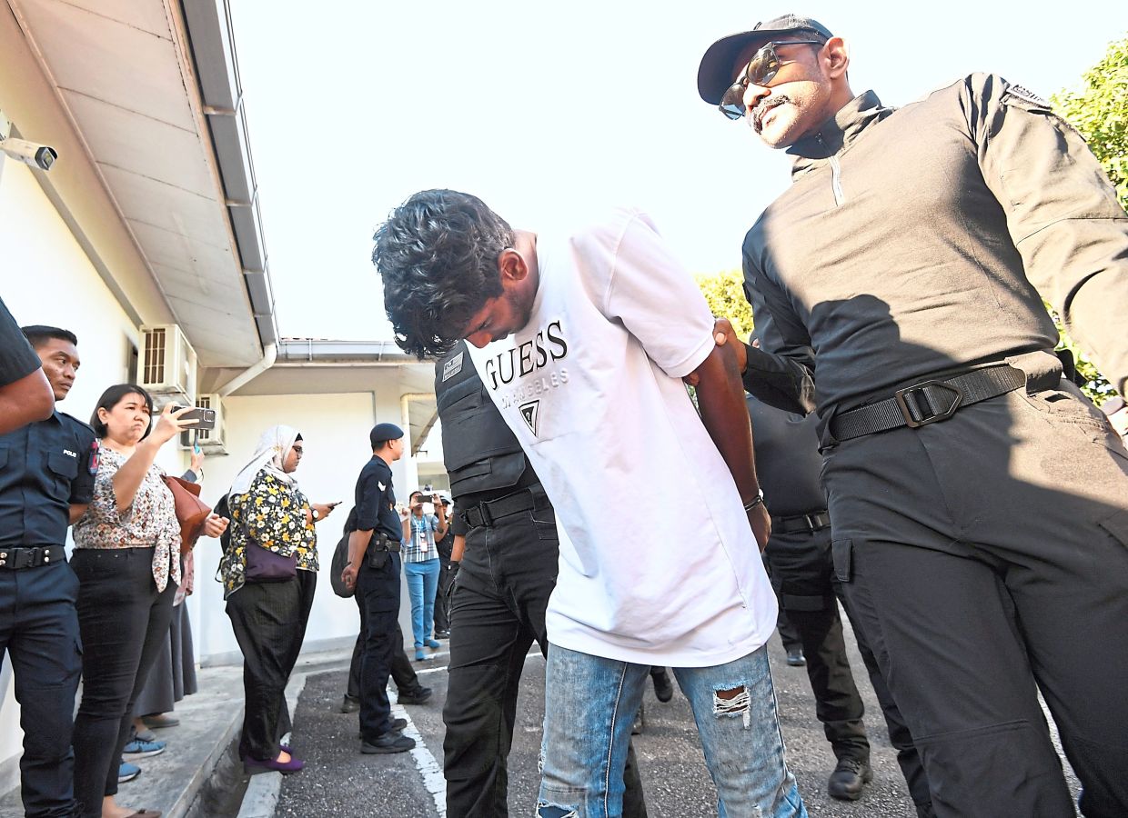 Hauled to court: Darvien being escorted by a cop as he arrives at the Sepang Magistrate’s Court. — AZHAR MAHFOF/The Star