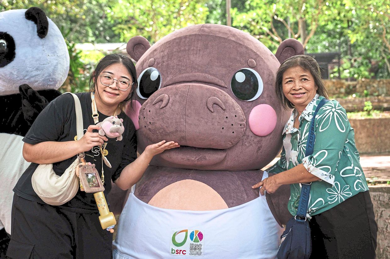 Adoring fans: Visitors taking a photo with a Moo Deng mascot at the Khao Kheow Open Zoo. — AFP
