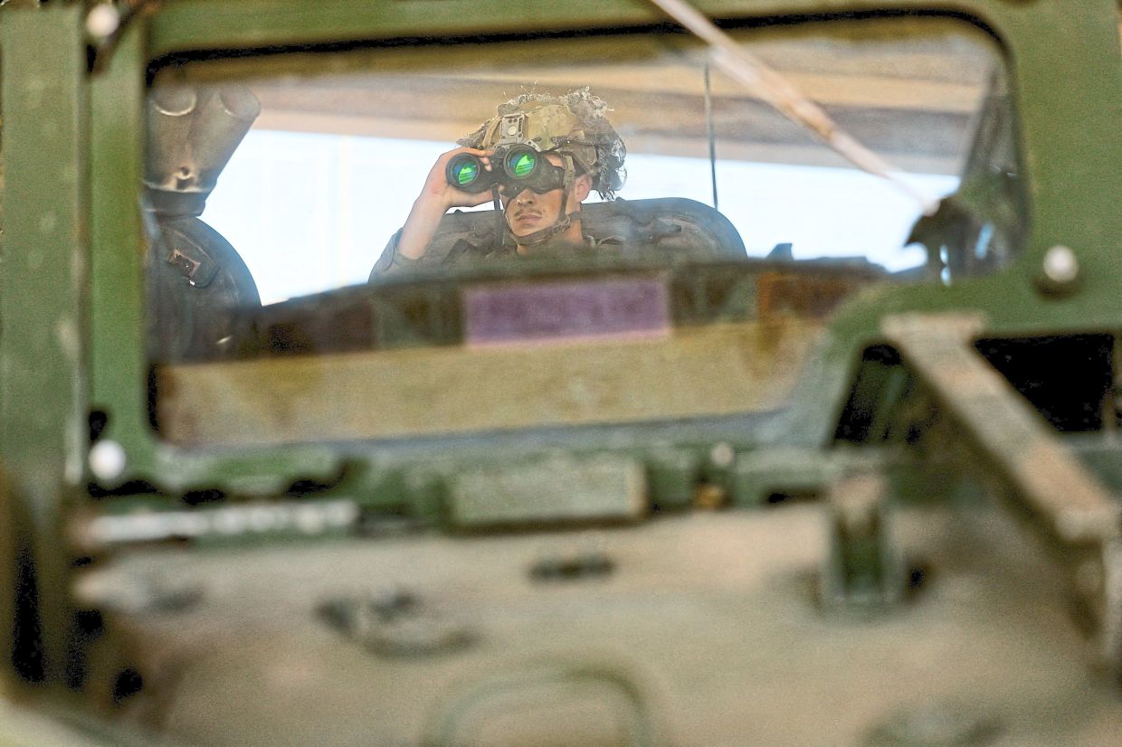 A US Army soldier using binoculars while riding a Stryker armoured vehicle at the US-Mexico border. — Reuters