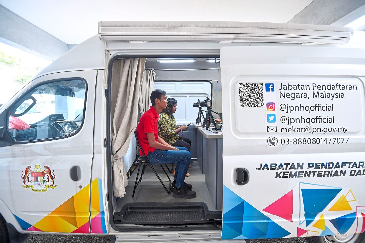 Preakas (left) attending to a senior citizen at the myIdentiti programme at Dewan MBSA in Kemuning Utama, Shah Alam. — Photos: IZZRAFIQ ALIAS/The Star