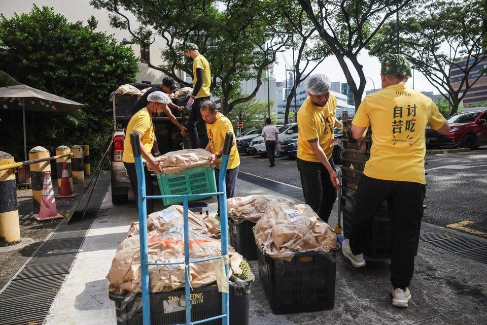 Workers unloading durians from a truck at 99 Old Trees Durian parlour in Outram. - Photo: ST