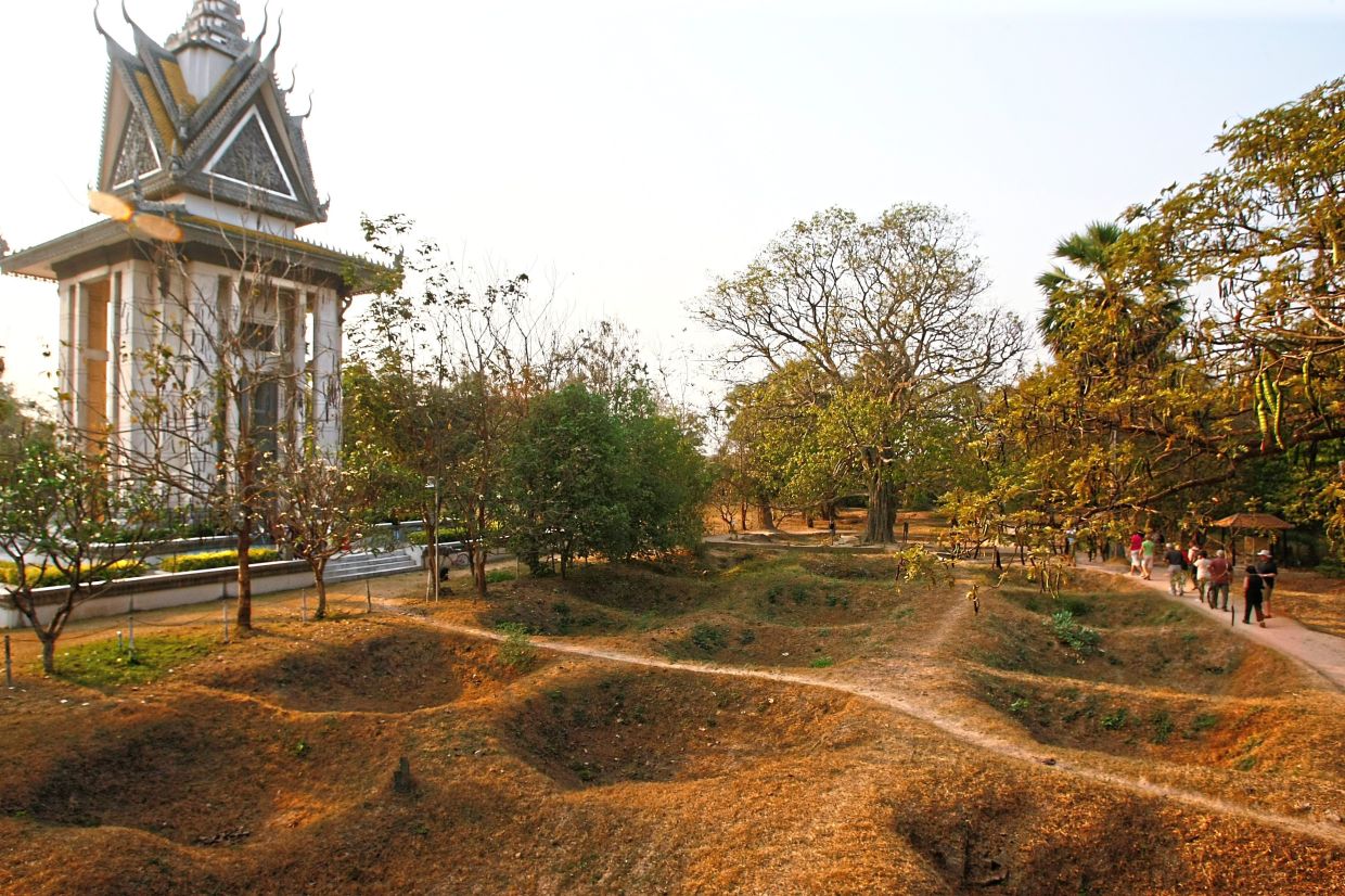 Never forget: Visitors walking by the mass grave of the victims of the Khmer Rouge regime next to a memorial stupa filled with victims’ skulls in Choeung Ek. — AP