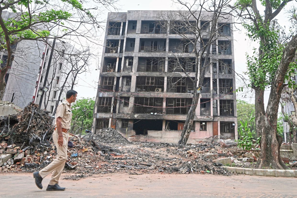 A policeman walking past buildings damaged in the June 12 crash. A