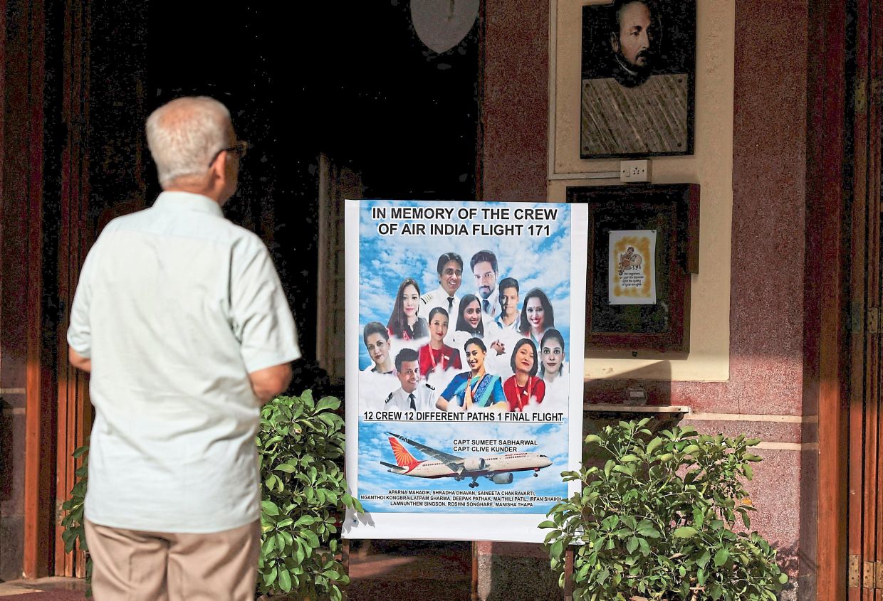  man praying in front of a placard during a memorial held for the deceased crew members.