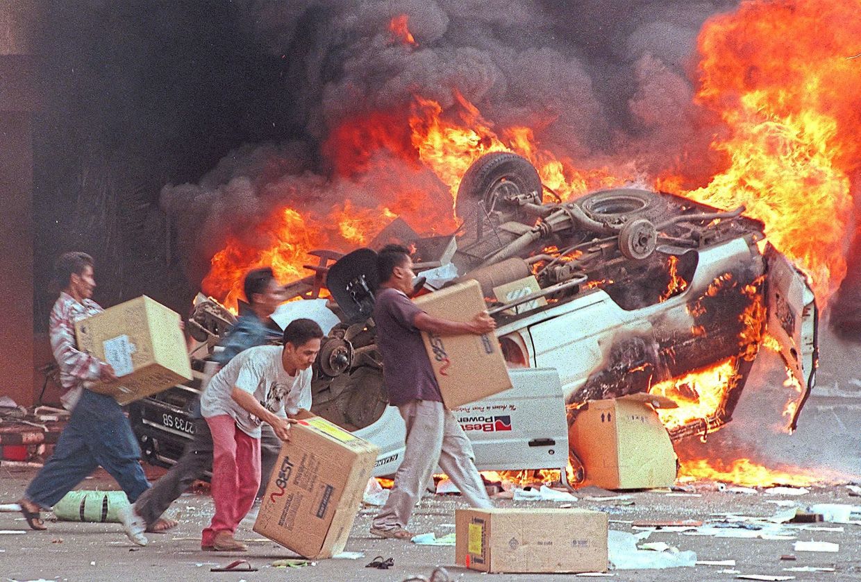 Mobs burning cars and looting Chinese-owned businesses in Jakarta on May 14, 1998. — AFP