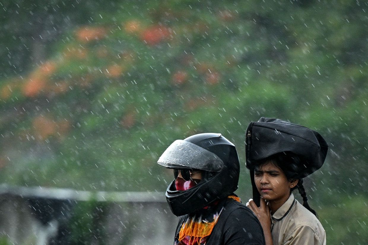 Commuters make their way along a road as it rains in Chennai on on Monday (July 14, 2025). -- Photo by R.Satish BABU / AFP
