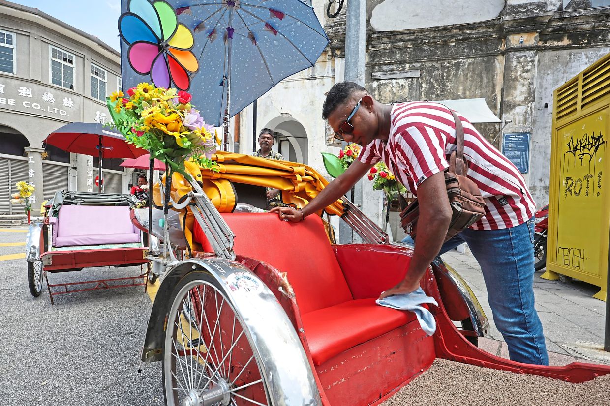 Ganapati wiping the seat of his trishaw while waiting for a customer at Armenian Street.