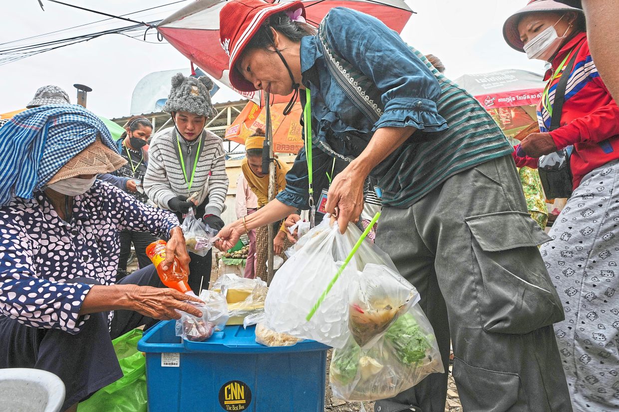 Garment workers buying food at a sidewalk in Ang Tako village. — AFP